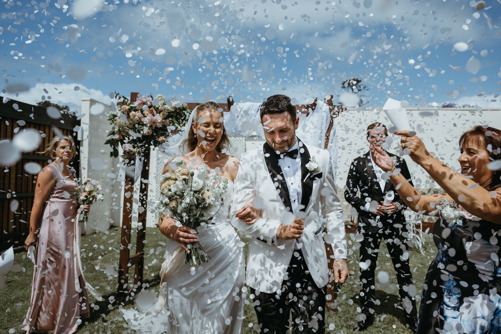 The newlyweds and their wedding party in a shower of confetti on the lawn