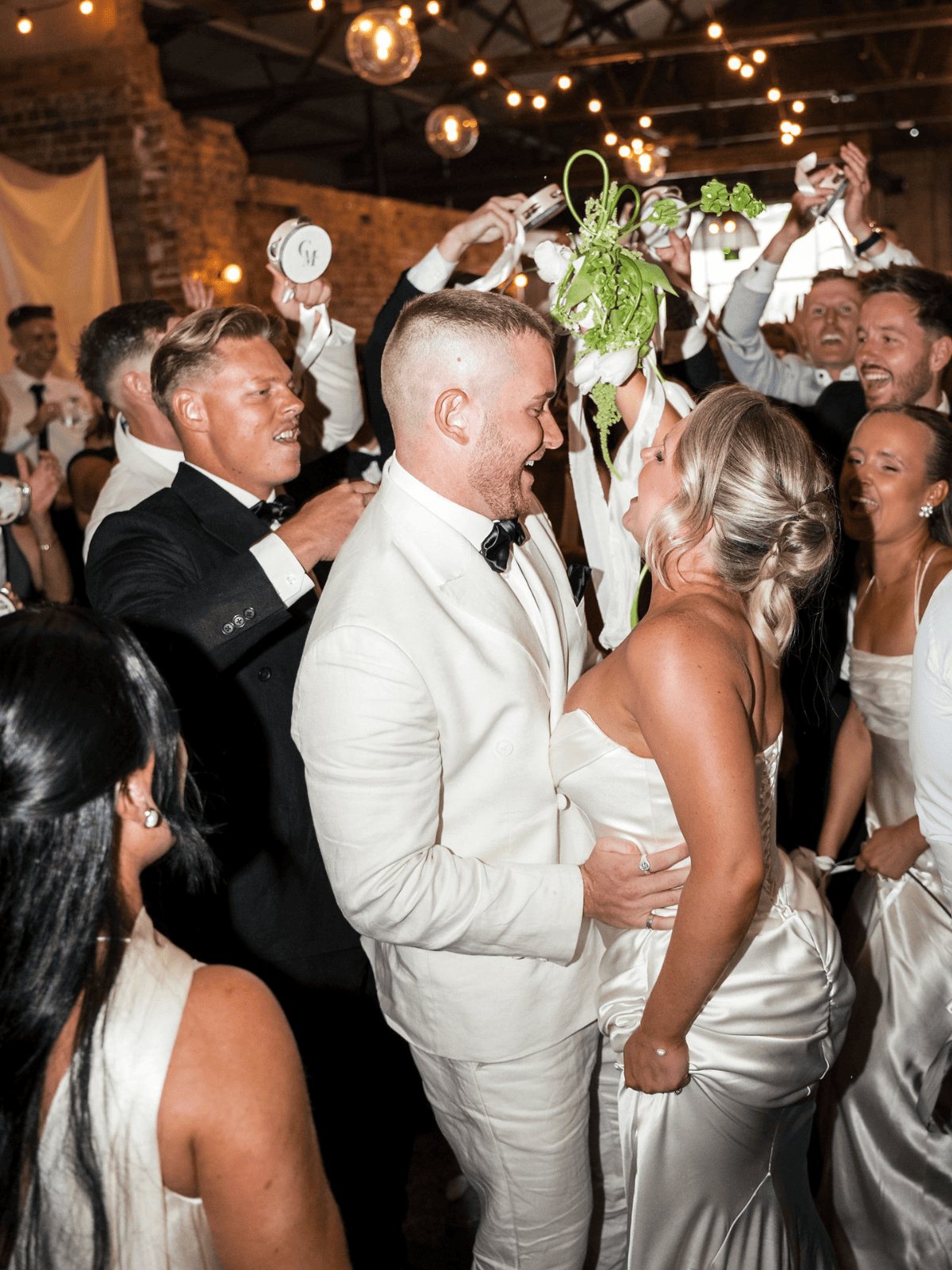 The couple in the middle of a packed dance floor under festoon lights