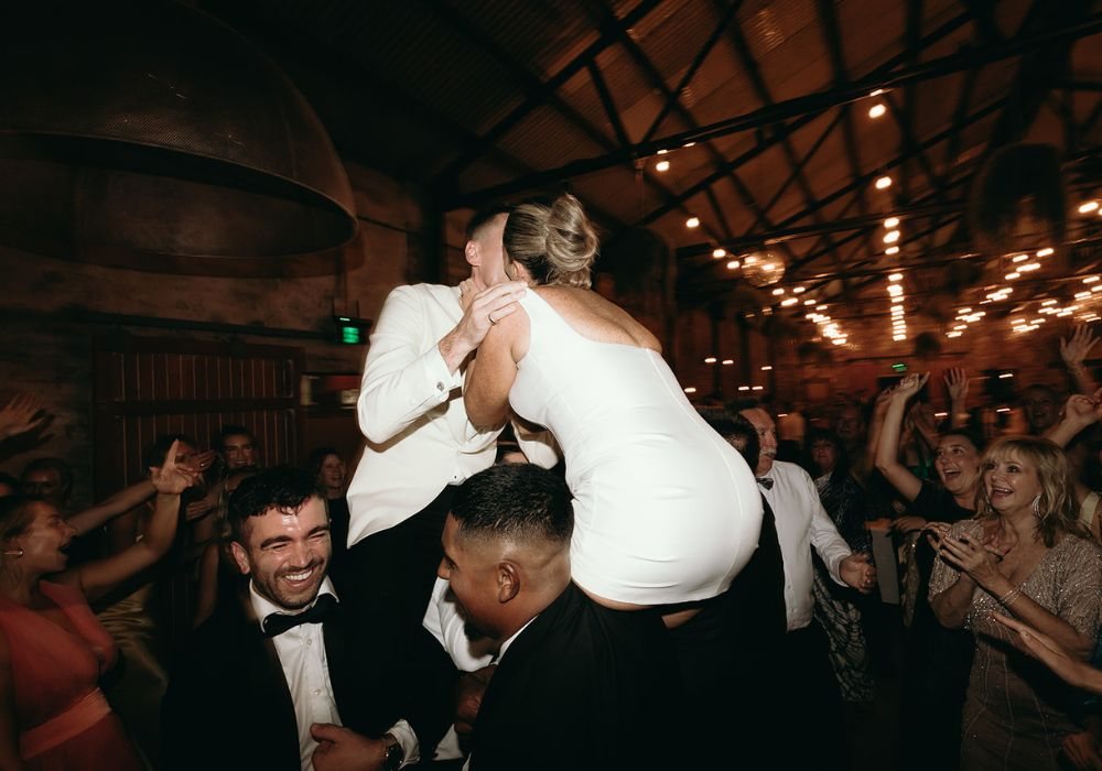 The bride lifted onto a guest&rsquo;s shoulders on the dance floor