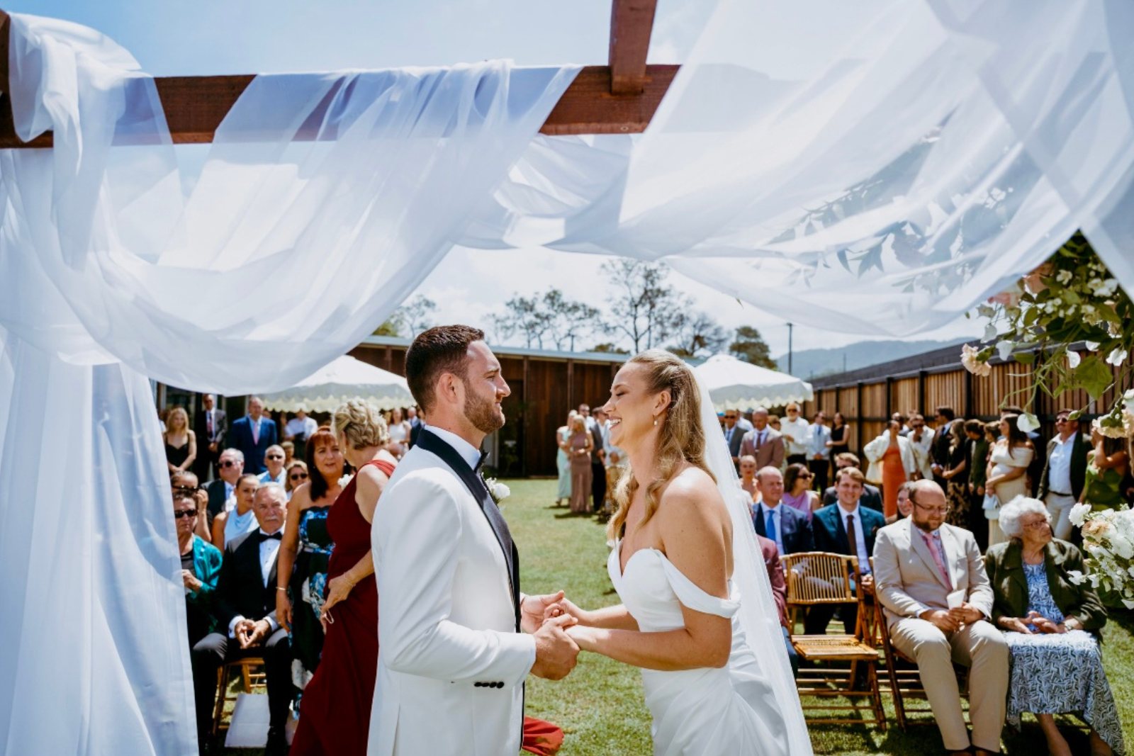 A couple laughing through their vows under draped white fabric